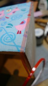 doppelseitiges Klebeband an den Schubladenrändern anbringen, damit das Satinband nicht verrutscht.