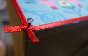 genau zielen und die Ecken mit Satinband vernageln. Auch die abgeschnittenen Enden werden mit Lack versiegelt.